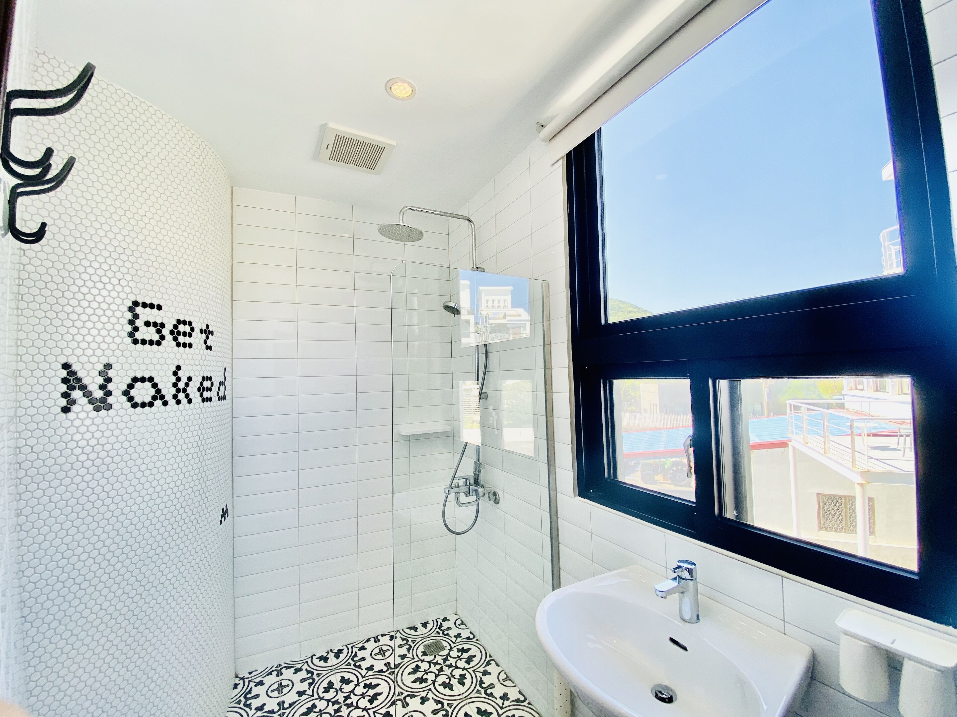 Een moderne badkamer met een douche, een wastafel en een groot raam.