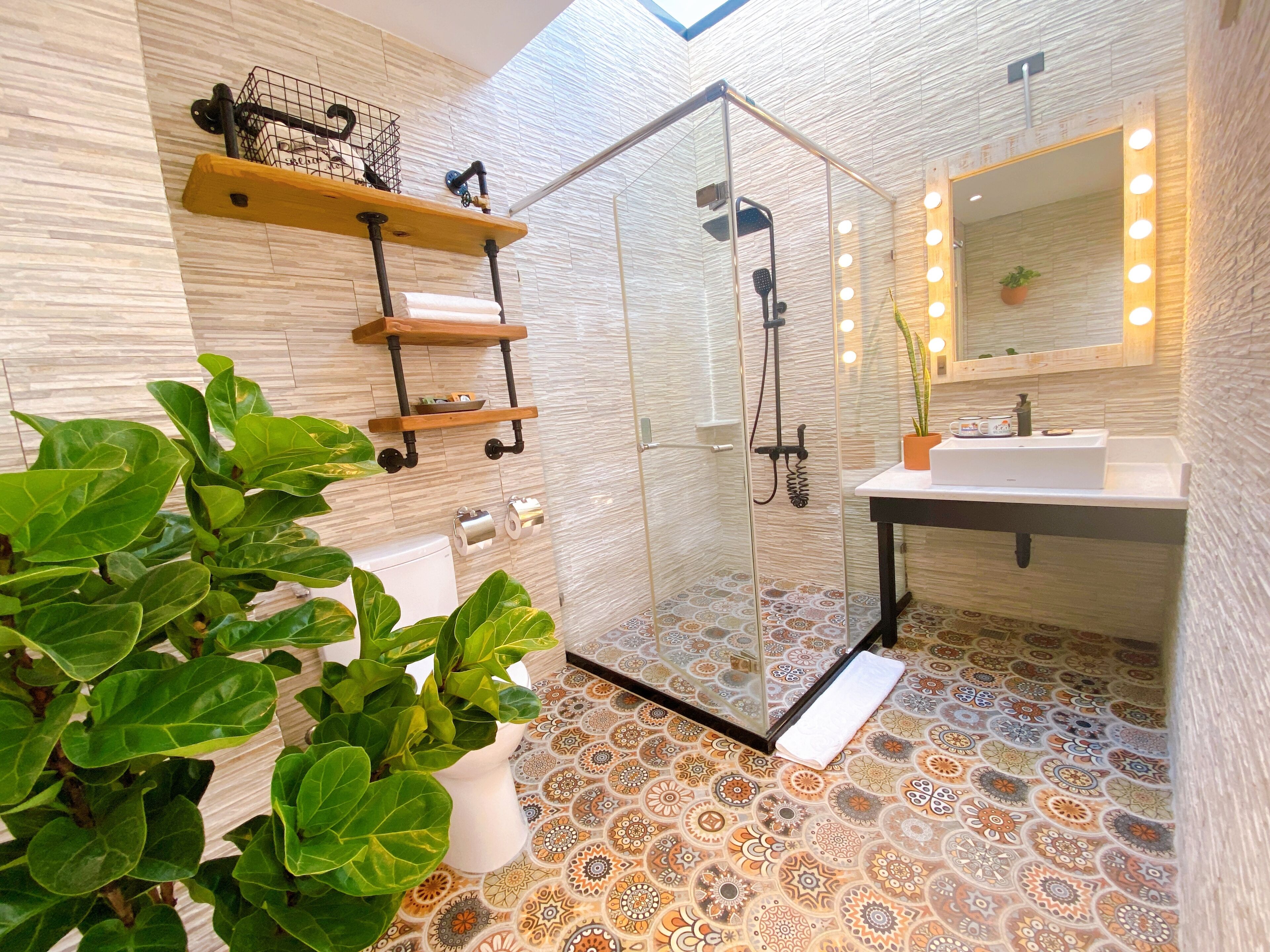 A modern bathroom with a glass shower enclosure, a sink with a mirror, and a patterned floor.