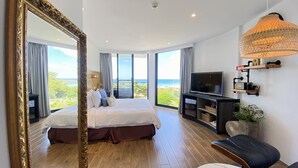 A modern bedroom with a large bed, a TV, and a view of the ocean. - Minimi Inn - SailRock Beach House (Hengchun)