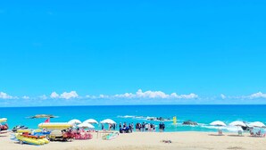 A beach with clear skies, a sandy shore, and several umbrellas and chairs. - Minimi Inn - SailRock Beach House (Hengchun)
