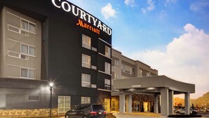 A Courtyard Marriott hotel with a modern facade, multiple entry points, and a parking lot. - Courtyard by Marriott New Orleans Westbank/Gretna (Gretna)