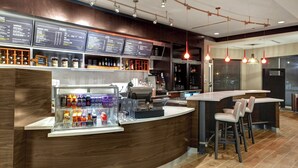 A modern bar area with a wooden counter, menu boards, and bar stools. - Courtyard by Marriott New Orleans Westbank/Gretna (Gretna)