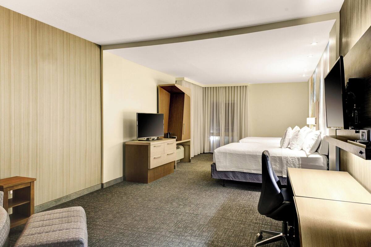 Une chambre d’hôtel équipée d’un lit, d’un bureau, d’une télévision et d’une armoire.