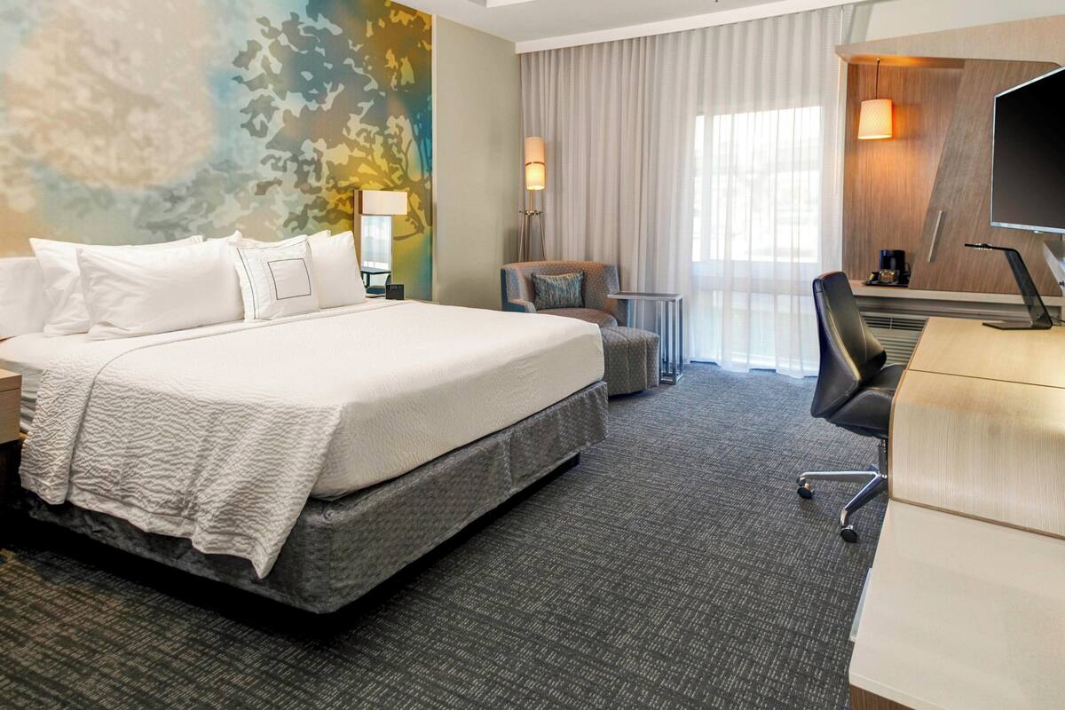 Une chambre d’hôtel avec un grand lit, un bureau, une chaise et un téléviseur.