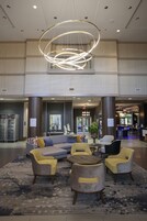A lobby with a modern chandelier, seating area with patterned chairs, and a reception desk.