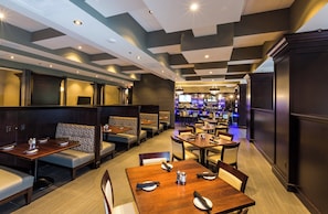 Un restaurante con cabinas y mesas, un área de bar y un diseño de techo moderno.