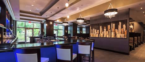 A bar area with multiple seating options, a cityscape mural, and a view of greenery outside.