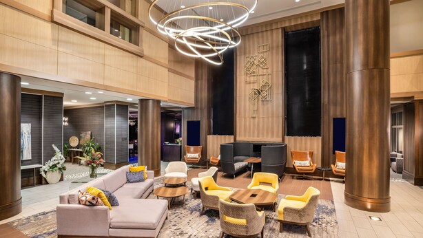 A spacious lobby with a modern sofa, multiple armchairs, a coffee table, and a TV. - Crowne Plaza Shenandoah - Woodlands Area by IHG (Shenandoah)