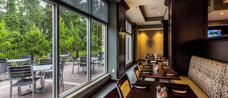 A restaurant with large windows, outdoor seating, and a modern interior design.