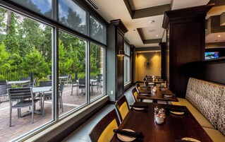 Un restaurante con amplios ventanales, terraza y una decoración interior moderna.