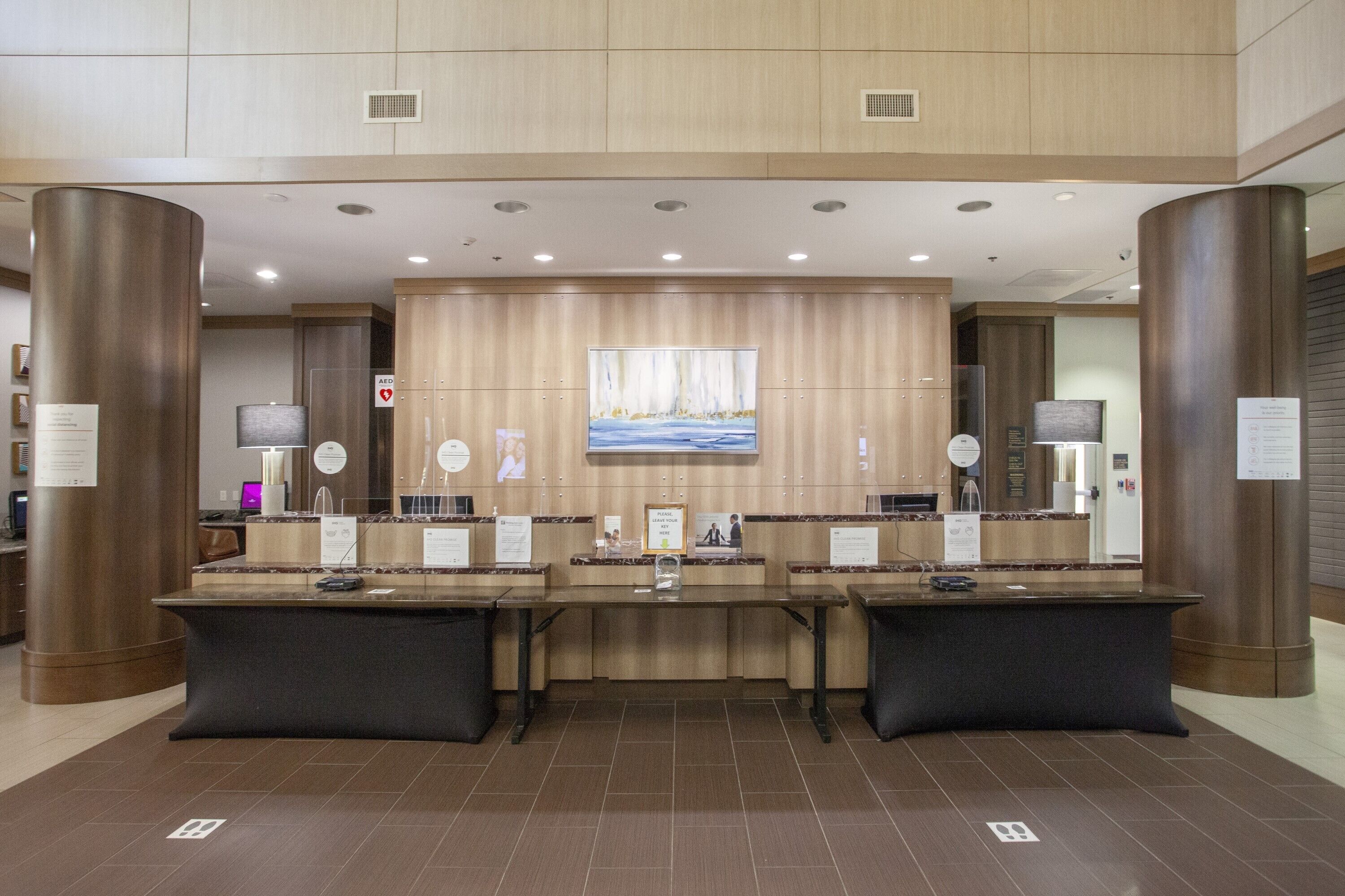 A reception area with a wooden panel wall, a large painting, and multiple reception desks.