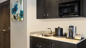 A modern kitchen with dark wood cabinets, a stainless steel sink, a microwave, and a coffee maker. - Crowne Plaza Shenandoah - Woodlands Area by IHG (Shenandoah)