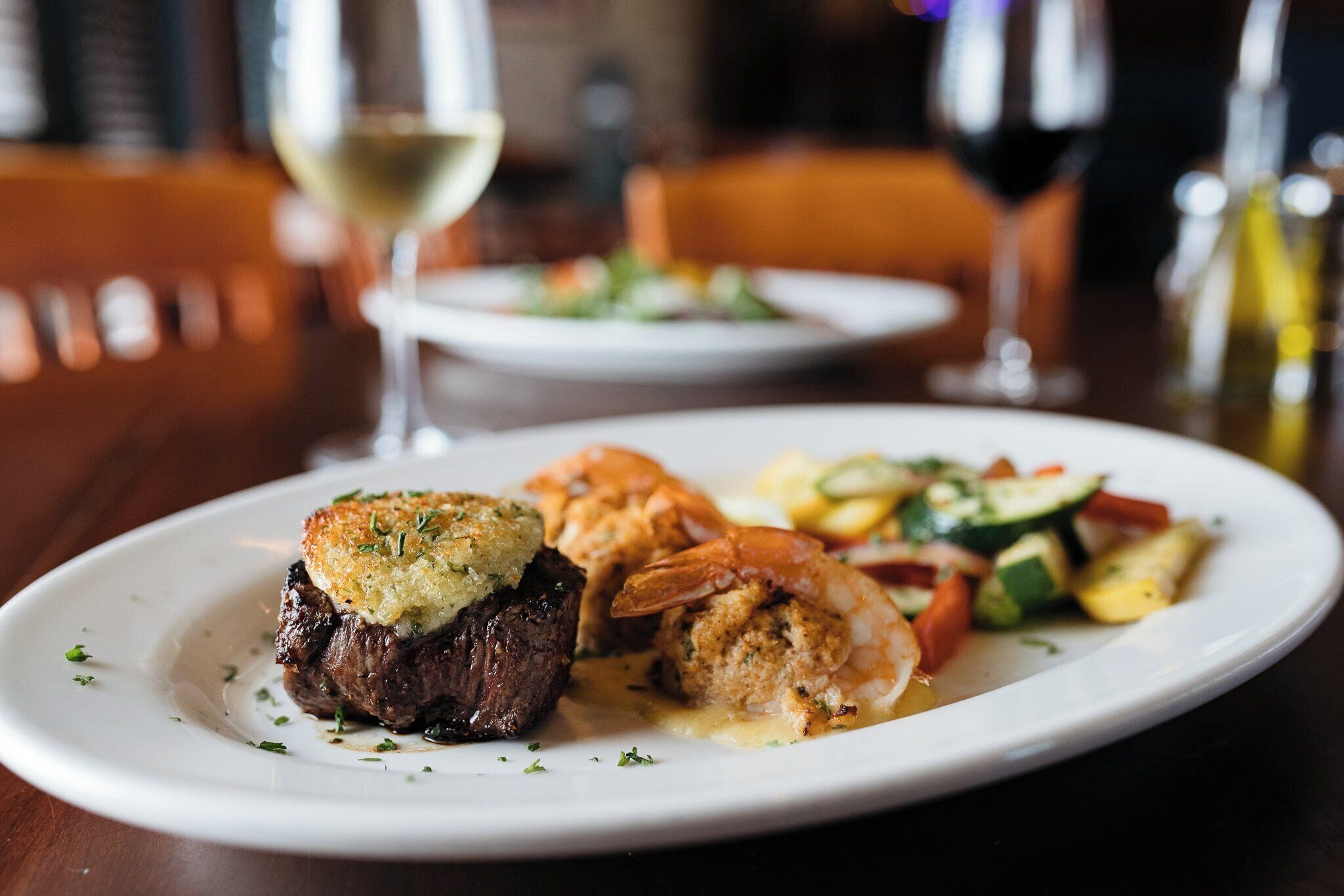 A plate of food with a steak, shrimp, and vegetables.