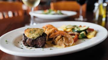 A plate of food with a steak, shrimp, and vegetables.
