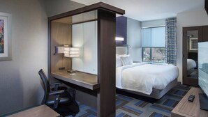 A hotel room with a bed, a desk with a chair, a desk lamp, a television, and a window with curtains. - SpringHill Suites by Marriott Houston Hwy. 290/NW Cypress (Houston)