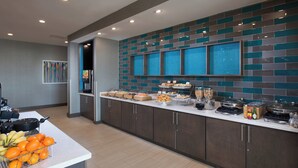 A modern kitchen with a long counter, various food items, and a tiled backsplash. - SpringHill Suites by Marriott Houston Hwy. 290/NW Cypress (Houston)