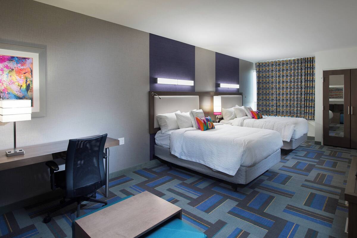 Une chambre d’hôtel avec deux lits, un bureau et une chaise.