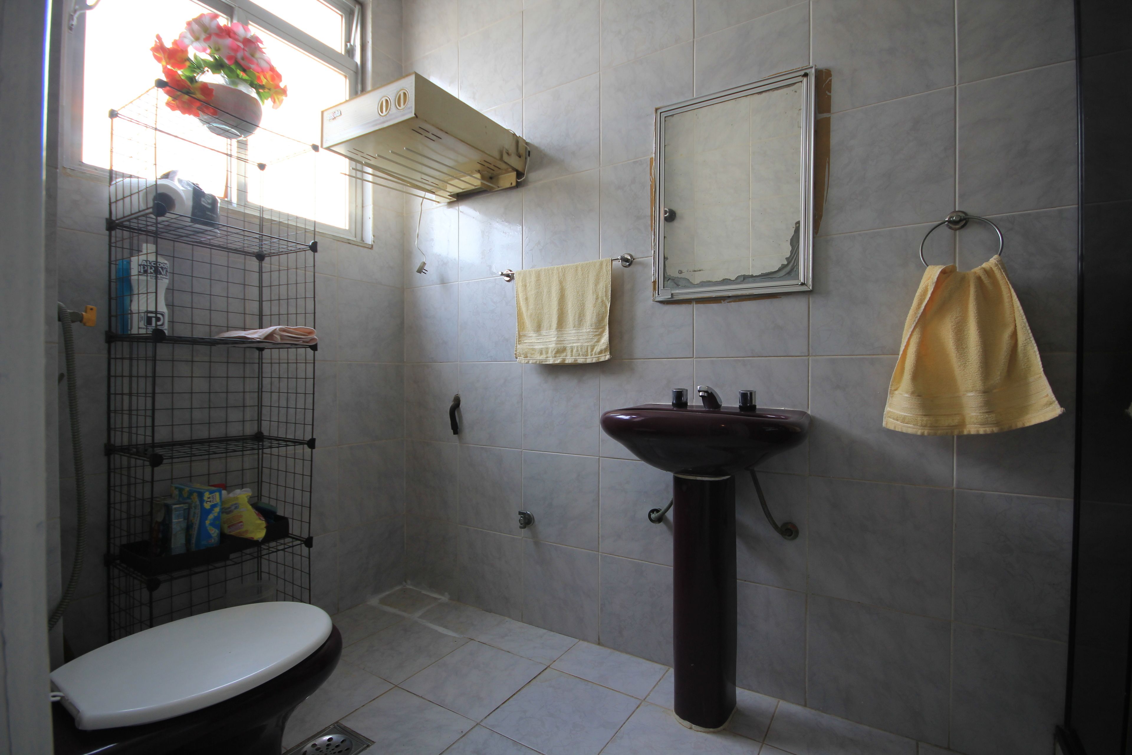 Une salle de bain équipée de toilettes, d’un lavabo, d’un miroir et d’étagères contenant des articles de toilette.