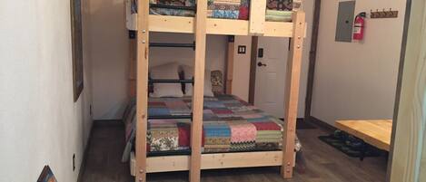 Ein Stockbett mit Decke, ein Holztisch und ein Feuerlöscher an der Wand.