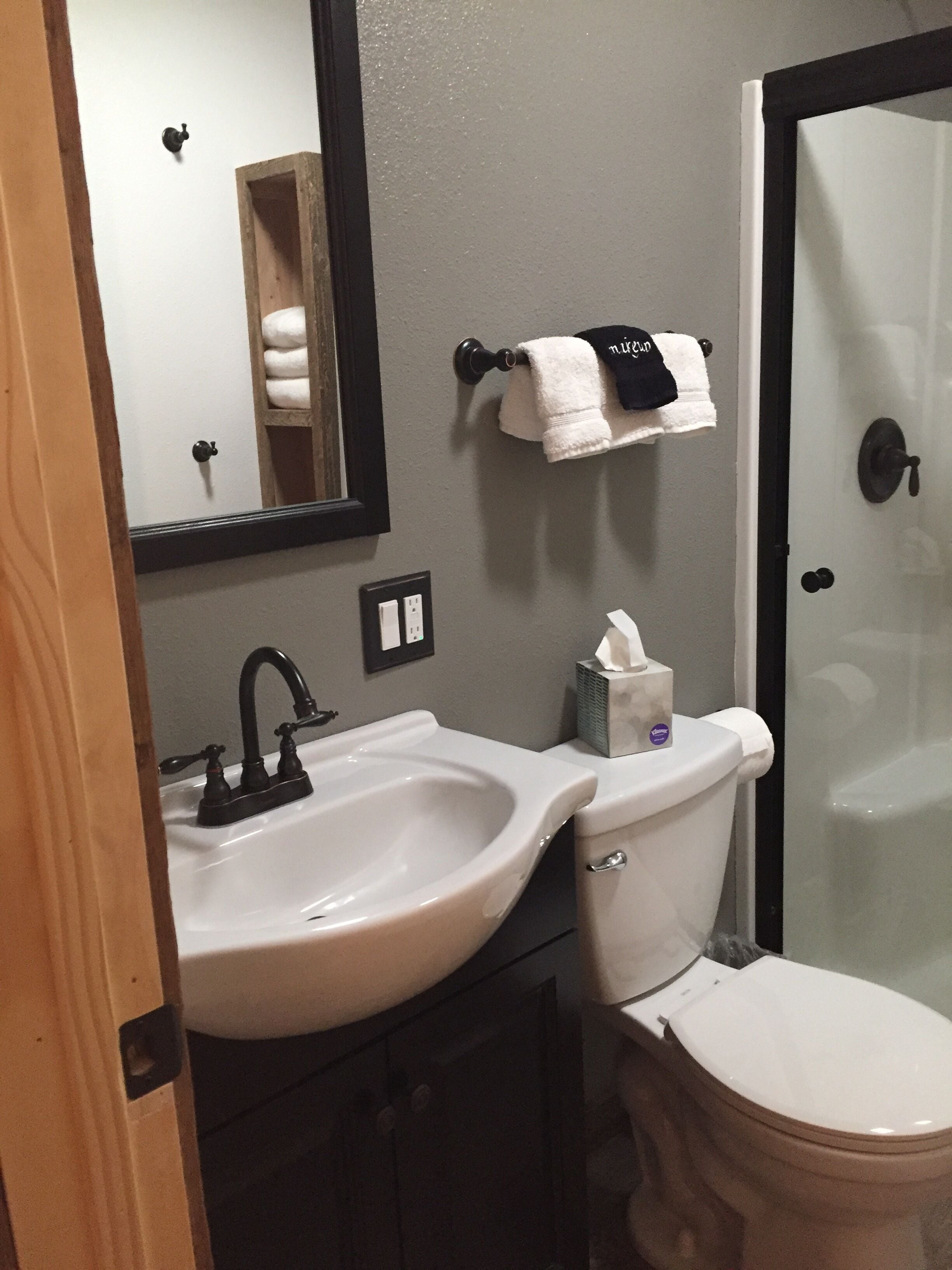 Un bagno con un lavandino bianco, un water e una cabina doccia in vetro.