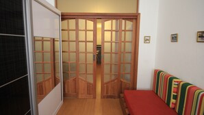 A room with a sliding door, a bed with striped bedding, and a small table. - Ribeiro 612 (Rio de Janeiro)