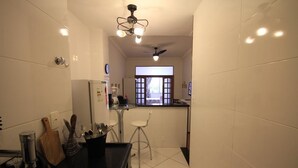 A compact kitchen with a black countertop, a small bar stool, and a window with a view. - Ribeiro 612 (Rio de Janeiro)