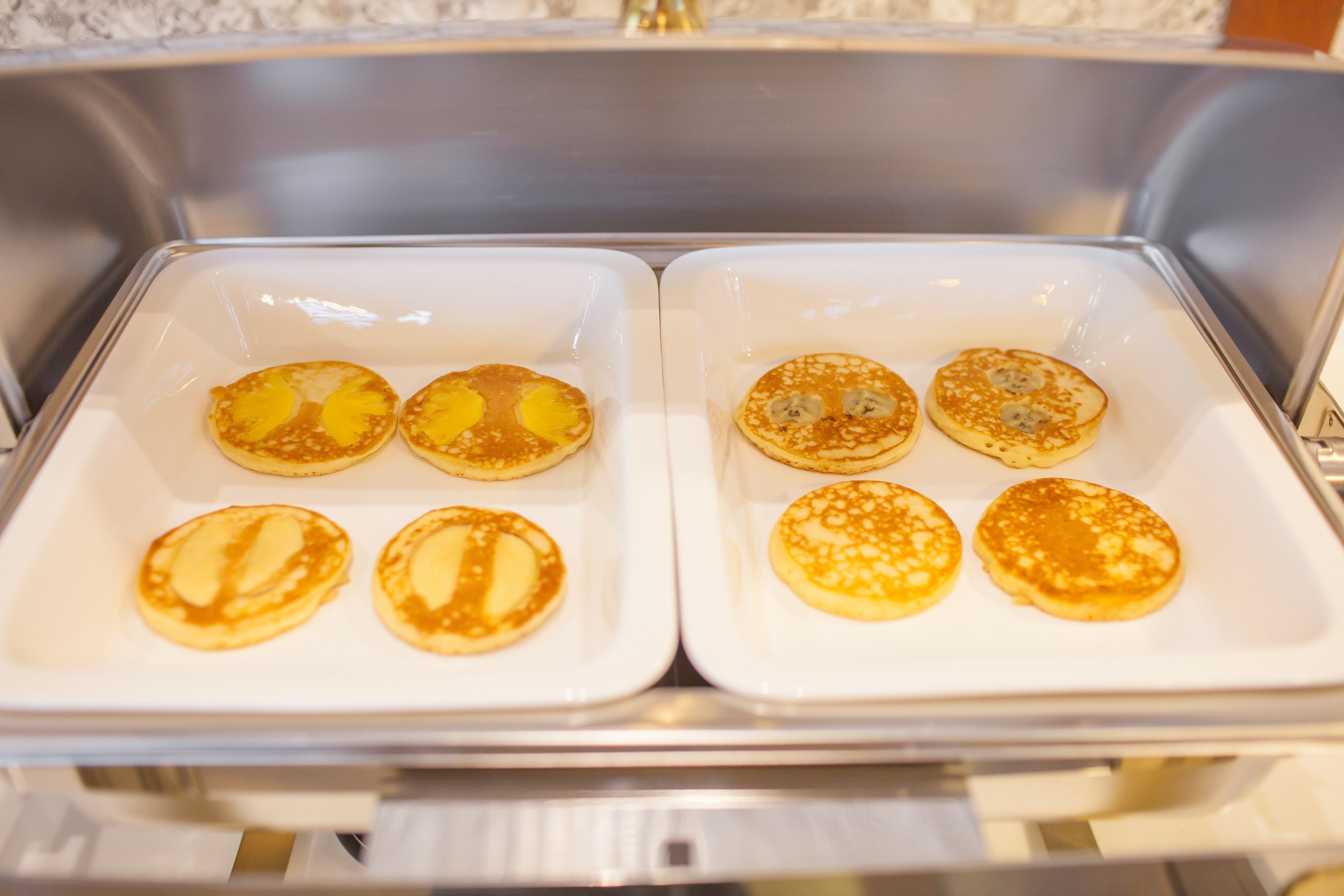 A kitchen with two white trays containing pancakes.