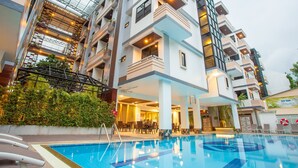 Um hotel moderno com piscina, várias varandas e áreas de estar internas.