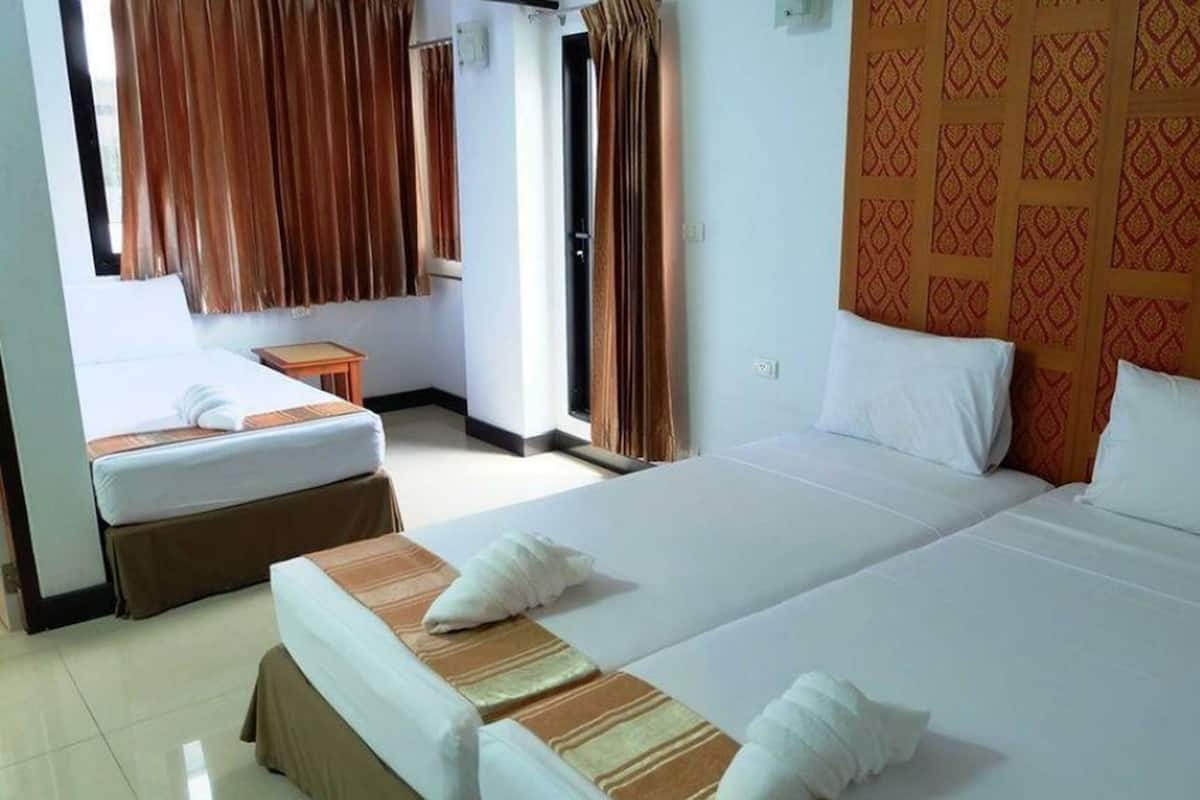 Une chambre d’hôtel avec deux lits, une petite table et une fenêtre avec des rideaux.