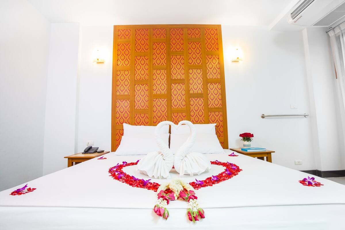 Une chambre d’hôtel comprenant un lit, une table de chevet, un téléphone fixé au mur et un panneau décoratif mural.