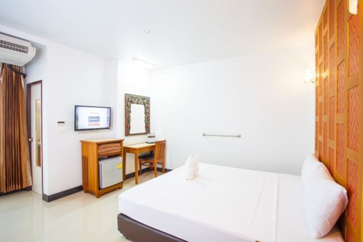 Une chambre d’hôtel comprenant un lit, un bureau, une chaise, une armoire et un miroir.