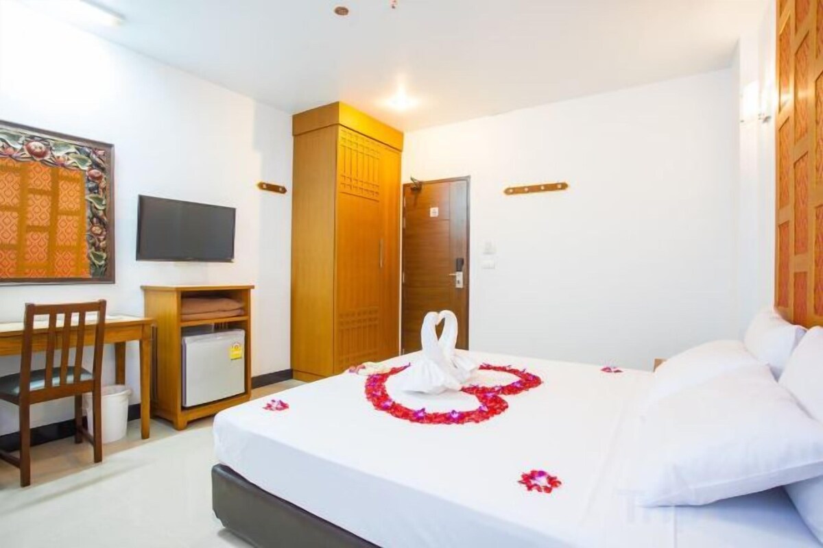 A hotel room with a bed, a desk, a television, and a wardrobe.