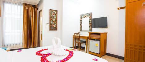Una habitación de hotel con cama, escritorio, televisor y armario.