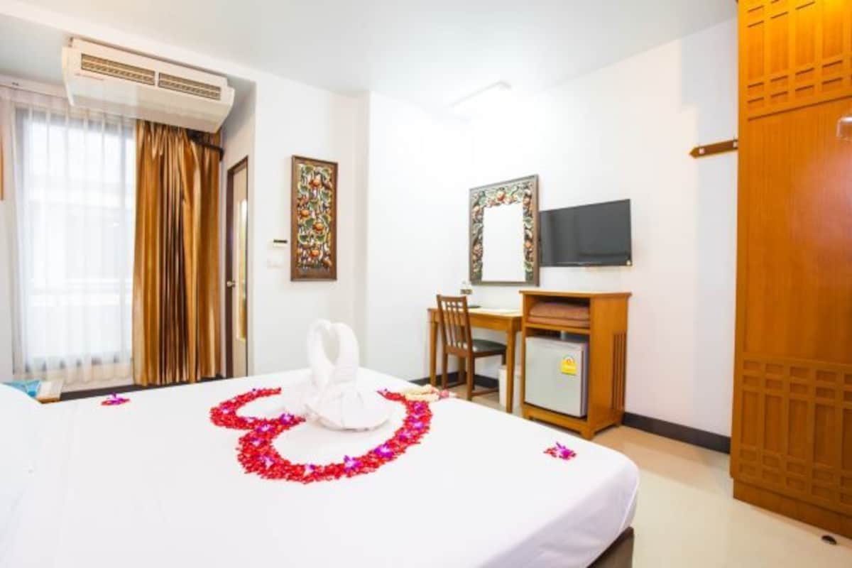 Camera d'albergo con un letto, una scrivania, una sedia, una televisione e un condizionatore d'aria.