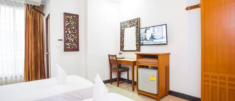 A hotel room with two beds, a desk, a television, and a small refrigerator.
