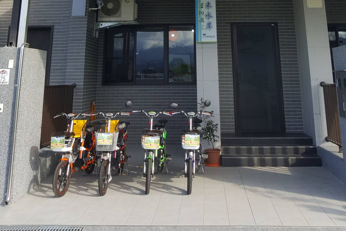A modern building with multiple floors, balconies, and a covered entrance area with bicycles parked outside.