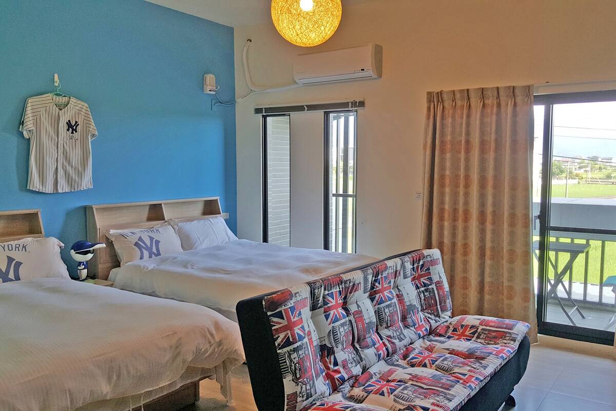 A hotel room with two beds, a sofa, and a balcony with a view.