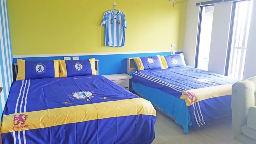 Ett hotellrum med två sängar, där varje säng är bäddad med blått och gult sänglinne med Chelsea FC-motiv.