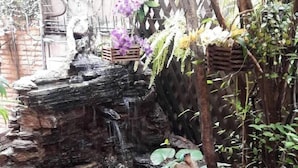 A garden with a small waterfall, various plants, and a wooden structure. - New Siam I (Bangkok)