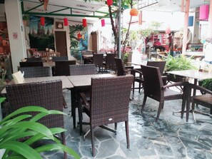 An outdoor cafe with wicker furniture and stone flooring.