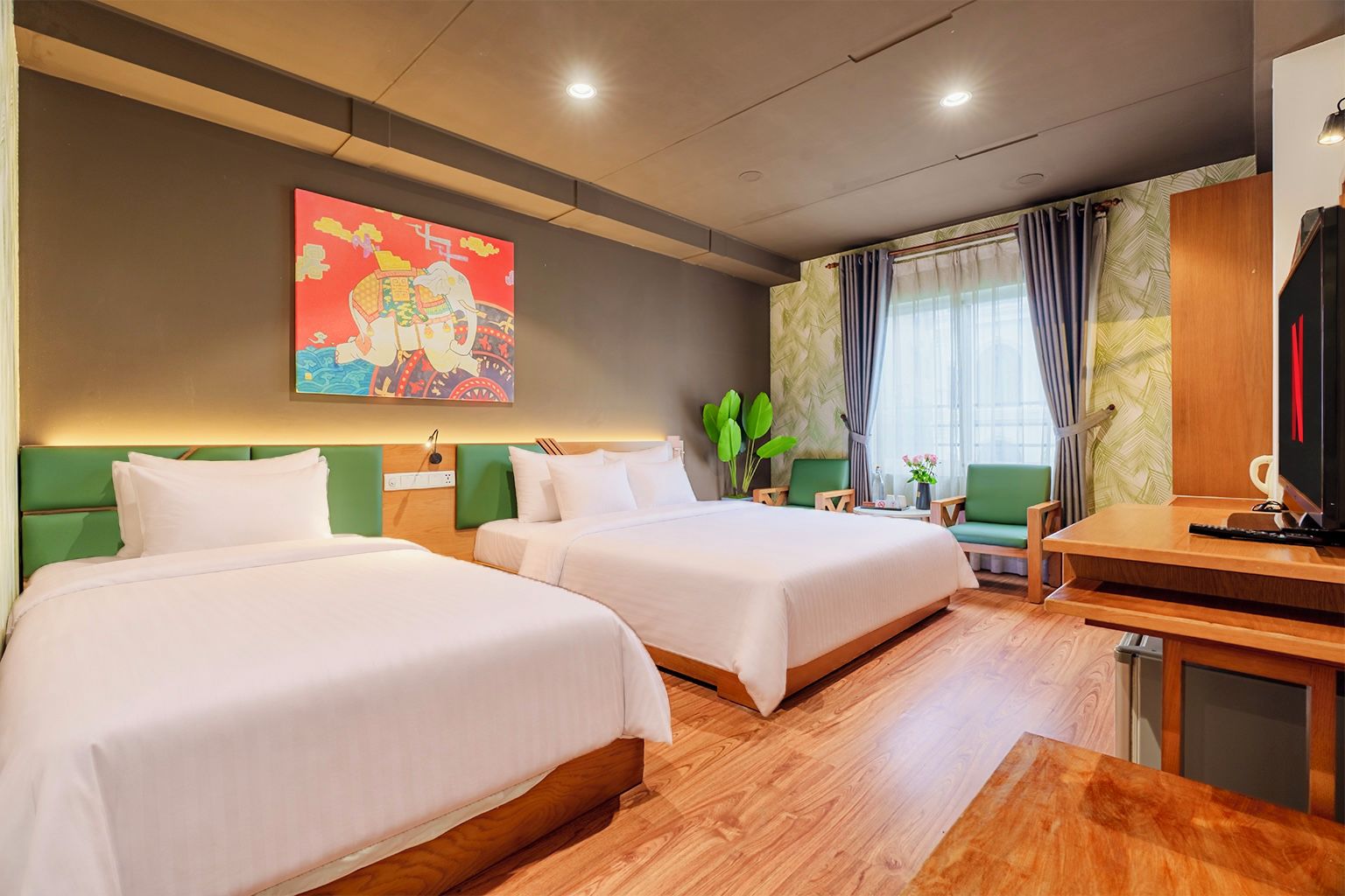 Ein Hotelzimmer mit zwei Betten, einem Schreibtisch, einem Fernseher und einem Bild an der Wand.