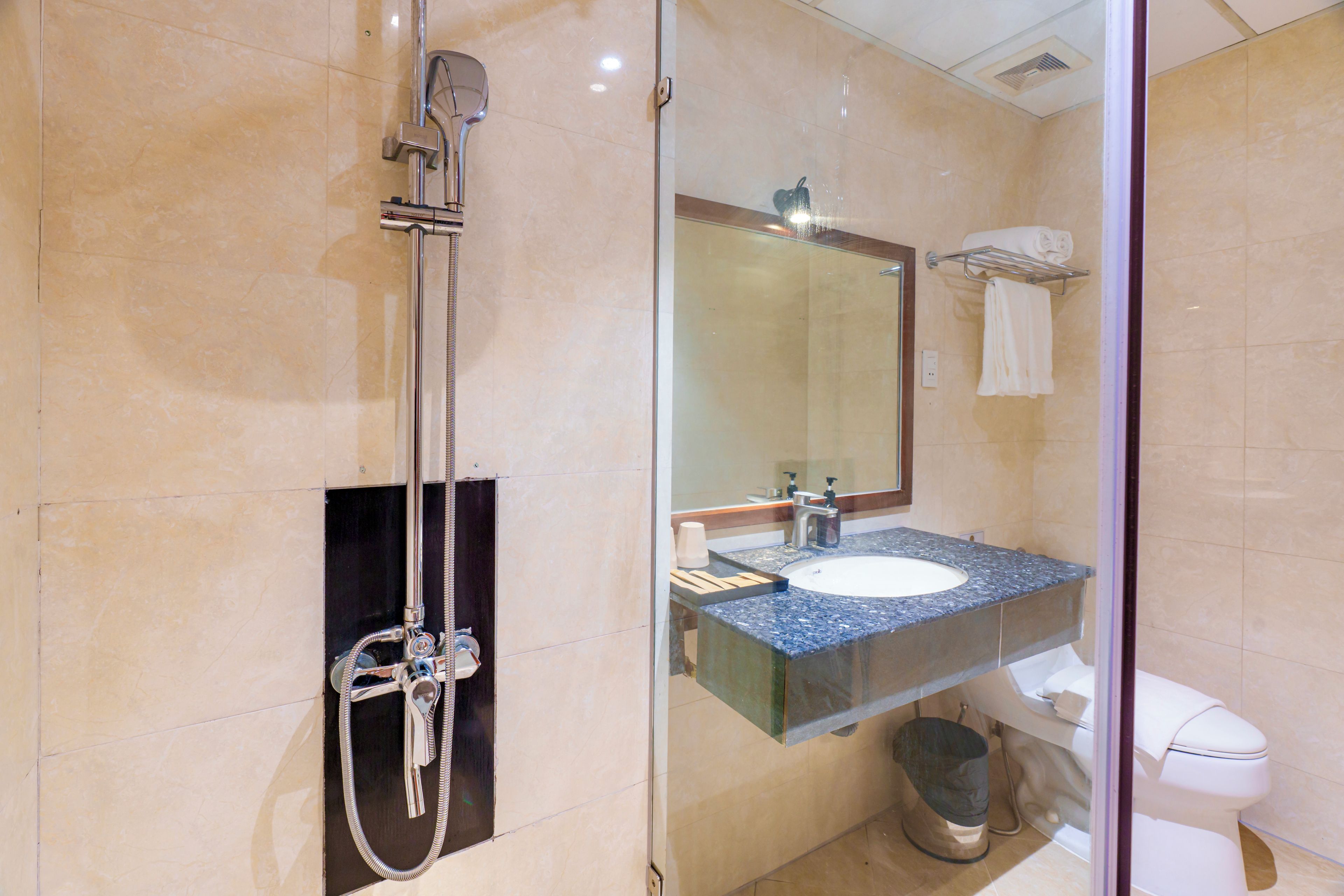 A modern bathroom with a glass-enclosed shower, a sink with a marble countertop, and a toilet.