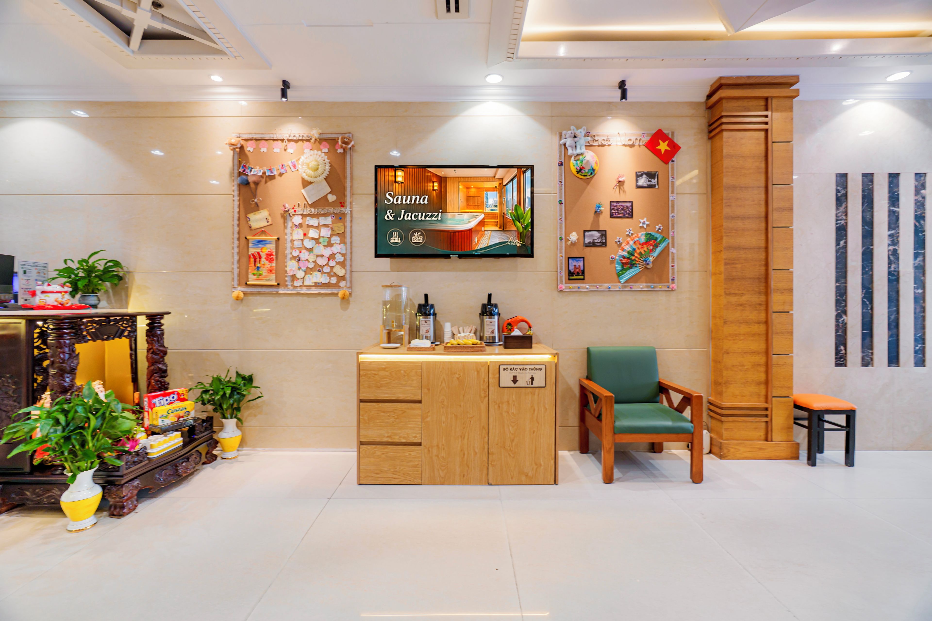 Un espace d’accueil doté d’un comptoir en bois, d’un écran de télévision affichant les mots « Sauna et jacuzzi », et d’un mur orné de divers éléments décoratifs.