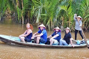 Un grupo de personas en una embarcación tradicional navegando por un río rodeado de vegetación densa.