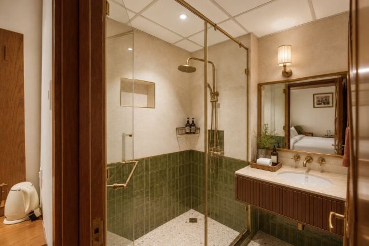 Un baño con ducha de vidrio, un lavamanos con espejo y un inodoro.