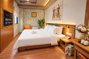 Une chambre d’hôtel avec un grand lit, une table de chevet avec un téléphone, une petite table avec une plante et un téléviseur fixé au mur diffusant Netflix.