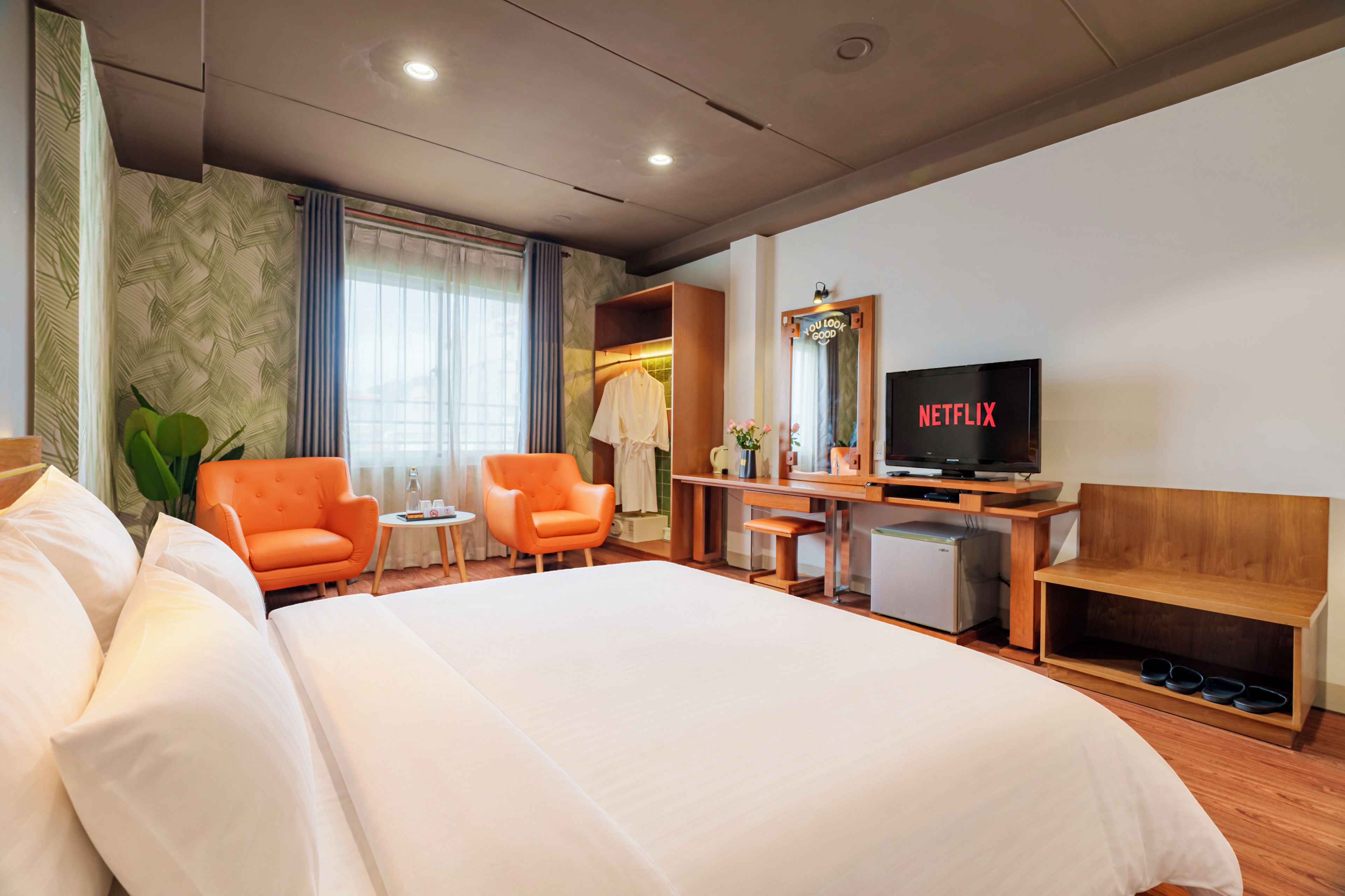 A hotel room with a bed, a desk, a chair, a TV, and a small refrigerator.