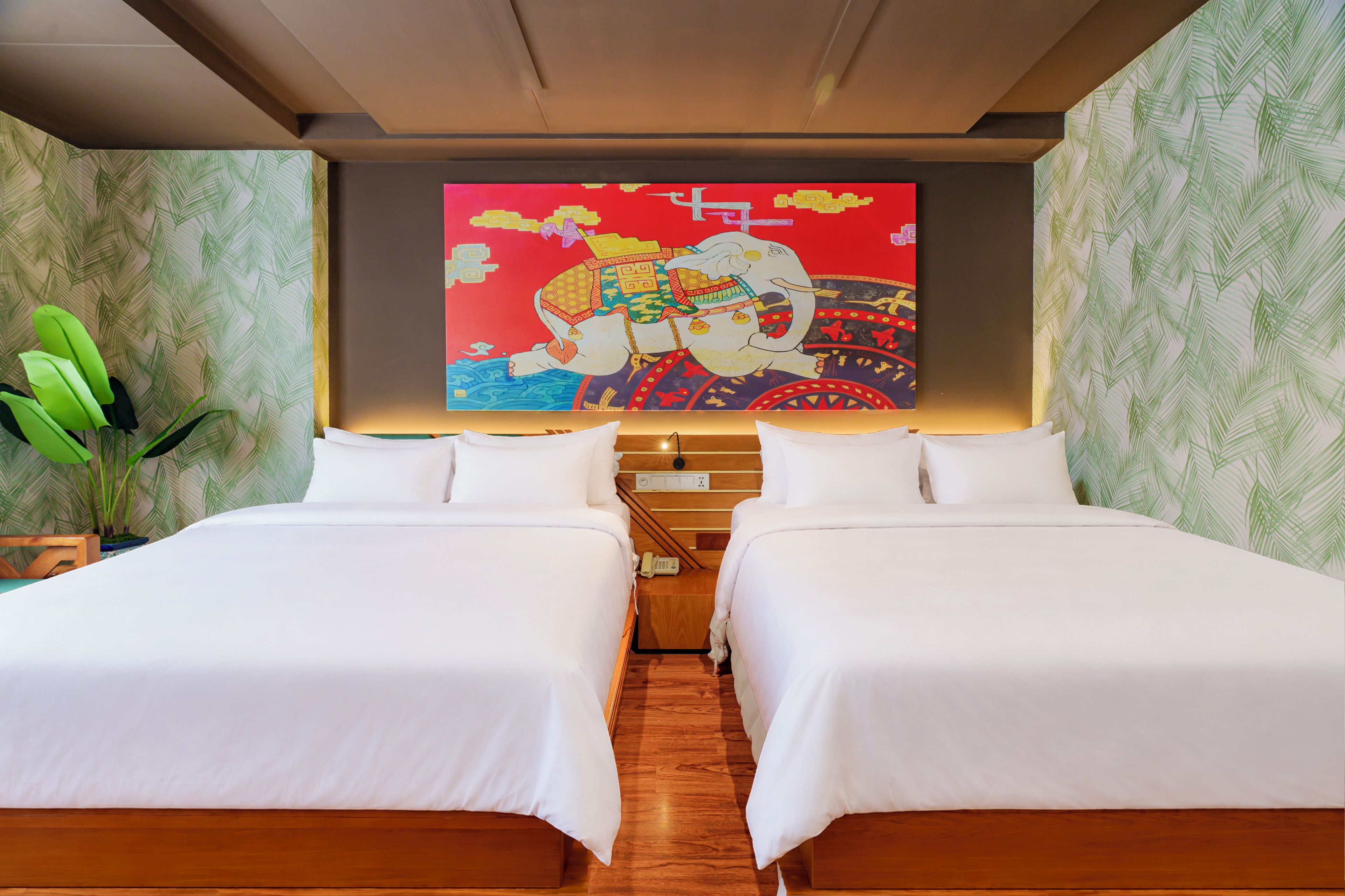 Ein Hotelzimmer mit zwei Betten, einer großen Wandmalerei und einer Pflanze.