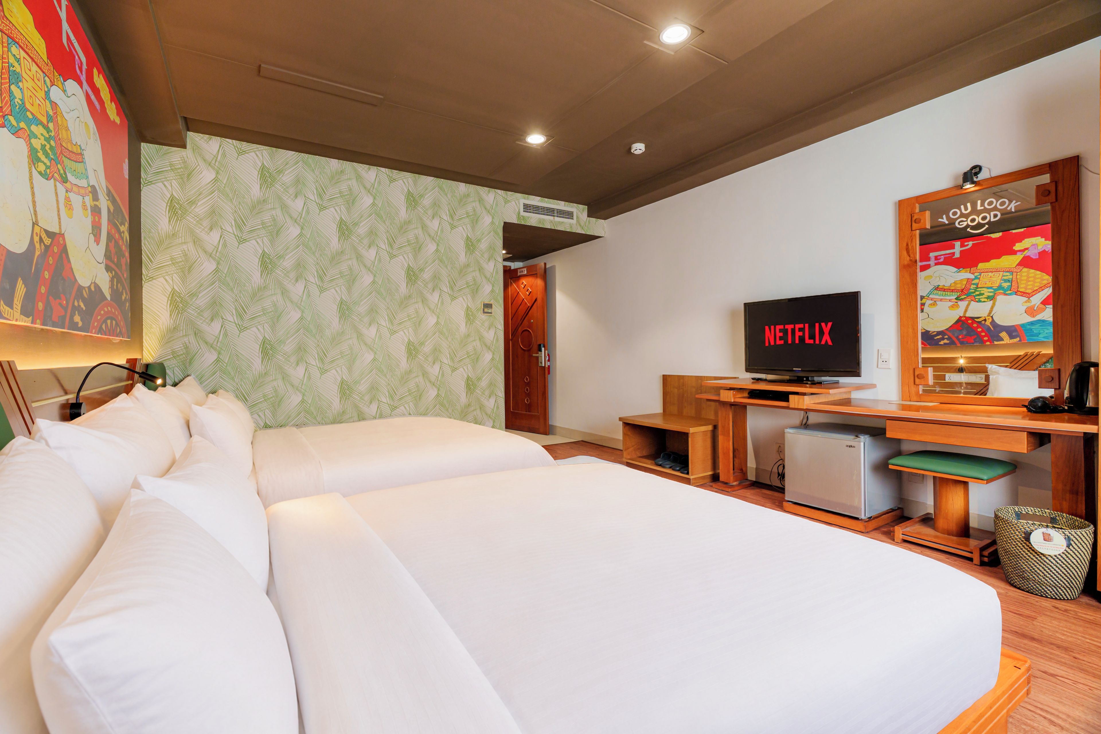A hotel room with a large bed, a desk with a television, and a wall with a decorative painting.