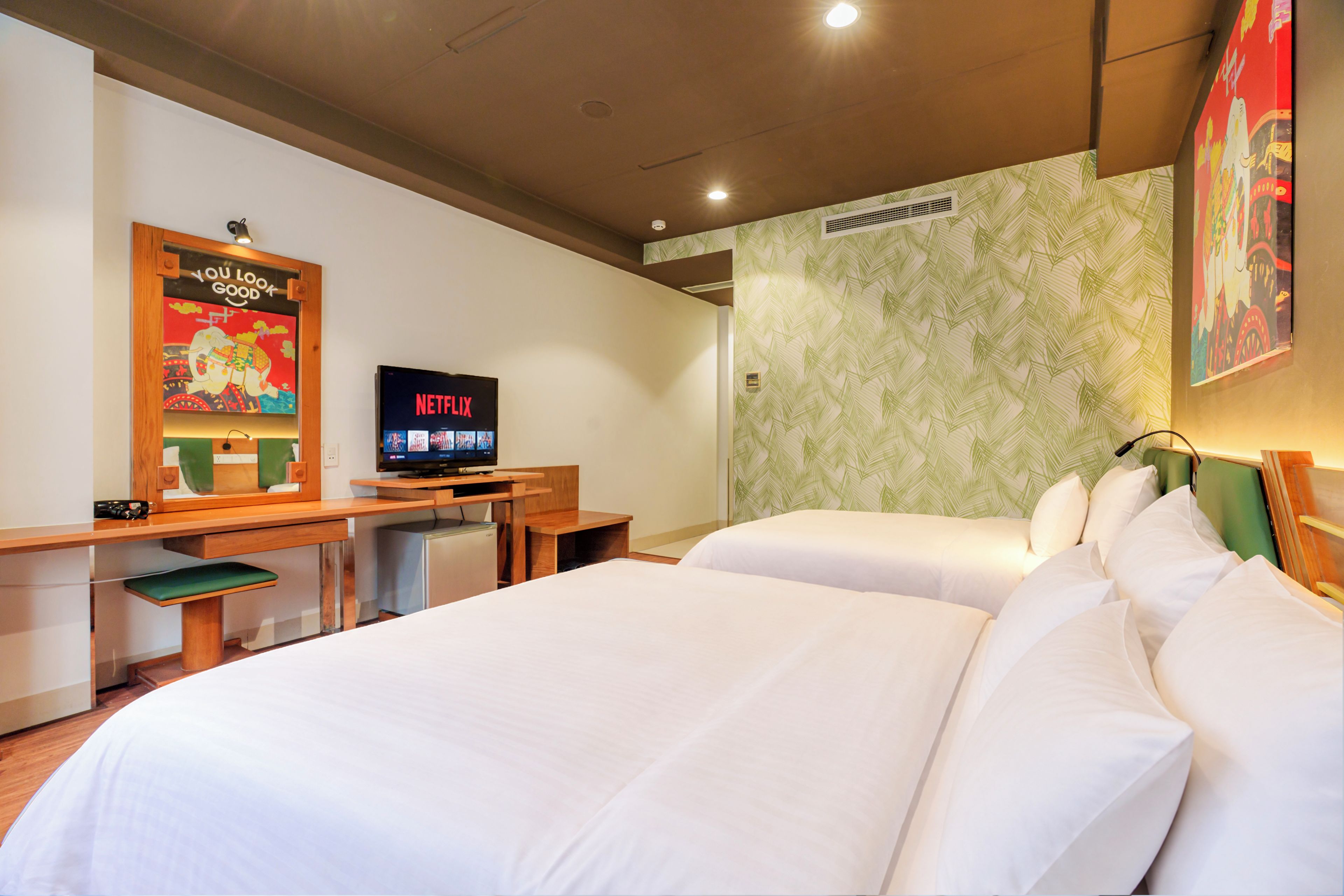 Una habitación de hotel con una cama, un escritorio con televisor y un cartel en la pared.
